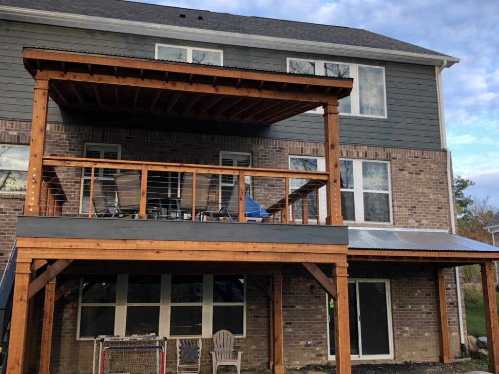 A Roofed Deck with timber posts and beams, with modern railings of wood and cable.